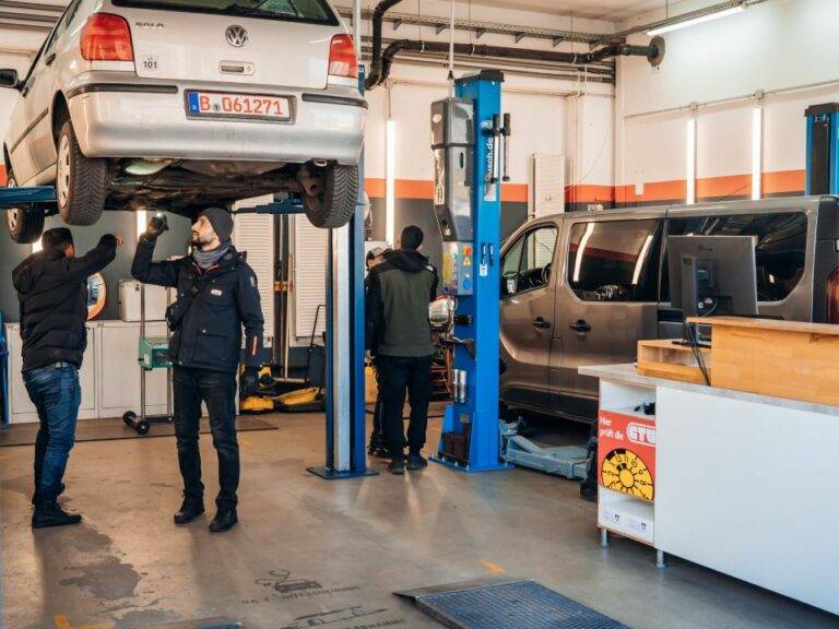 Techniker von EOS Fahrzeugtechnik bei der sorgfältigen Arbeit an einem Fahrzeug im Inneren der Filiale.