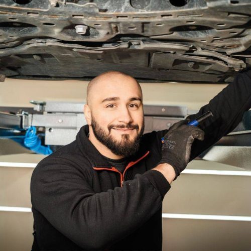 Ein lächelndes Mitglied des EOS Fahrzeugtechnik-Teams während der Fahrzeuginspektion.